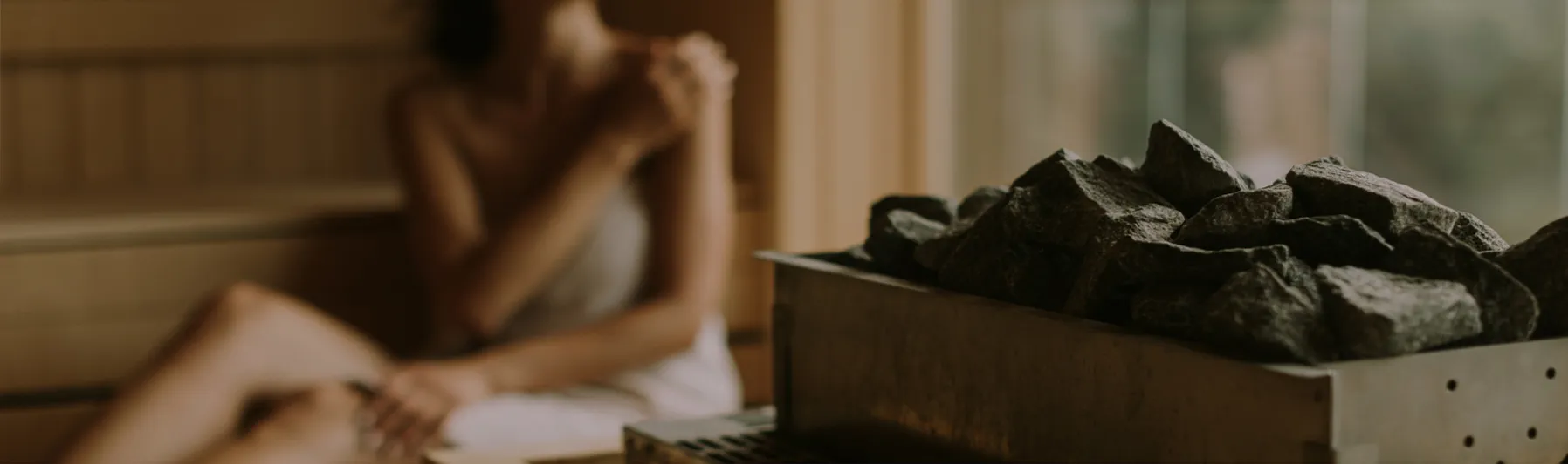 木造サウナ室でくつろぐ女性と熱した石