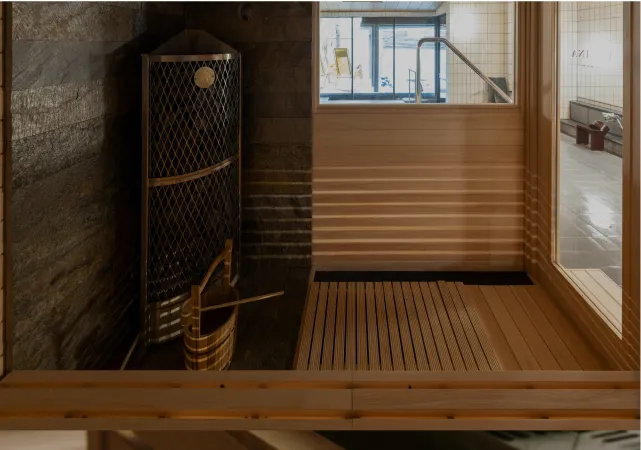 木造サウナ室でくつろぐ女性と熱した石